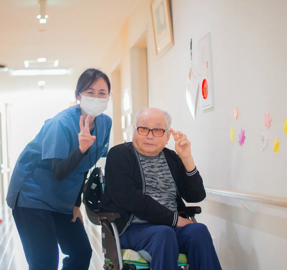 スタッフと入居者が廊下で笑顔で交流する様子。壁には作品が飾られている。
